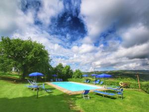 カスティリオーネ・ドルチャにあるFarmhouse in Val d'Orcia Charmの青い椅子とパラソルのあるプール