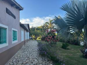 a stone walkway next to a building with flowers at Sítio Santa Felicità entre Guaratinguetá e Aparecida do Norte in Guaratinguetá