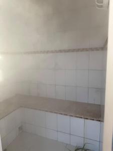 a bathroom with white tiled walls and a shelf at Sítio Santa Felicità entre Guaratinguetá e Aparecida do Norte in Guaratinguetá