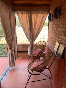 deux chaises assises dans une pièce avec une fenêtre dans l'établissement Chalé Bem Viver Ibitipoca, à Conceição da Ibitipoca