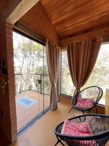 une chambre avec un balcon avec des chaises et une grande fenêtre dans l'établissement Chalé Bem Viver Ibitipoca, à Conceição da Ibitipoca