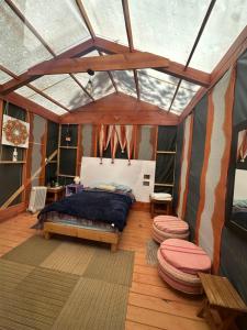 a bedroom with a bed and two stools in a room at Eko Aldea Kolybry in San Joaquín