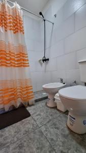 bagno con servizi igienici e tenda da doccia arancione e bianca. di ItuRanch II a Ituzaingó