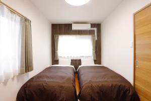 a small bedroom with two beds and a window at ウエストワン サウス 306 in Hitoyoshi