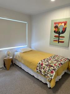 a bedroom with a bed and a painting on the wall at Mount Central Hideaway in Mount Maunganui