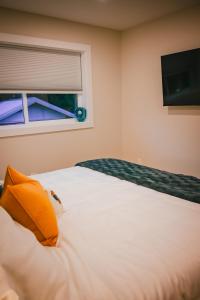 a bedroom with a bed with an orange pillow and a window at Courtenay Luxe Suite in Courtenay +10 photos