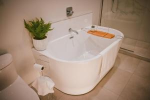 a white bath tub with a plant in a bathroom at Courtenay Luxe Suite in Courtenay