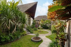 a garden in front of a house with a courtyard at Elitya Ubud Villa in Ubud
