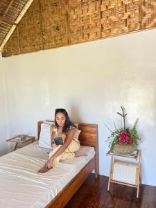 Eine Frau sitzt auf einem Bett und liest ein Buch. in der Unterkunft My Island Casitas in Baclayon + 13 Fotos