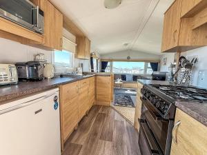 a kitchen with wooden cabinets and a stove top oven at Lovely 8 Berth Caravan At Manor Park Nearby Hunstanton Beach 23107S in Hunstanton