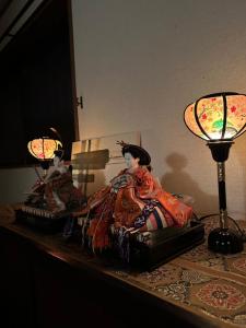 a couple of dolls sitting on a table next to lamps at Nara IROHA in Nara