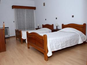 1 dormitorio con 2 camas, 2 mesas y una ventana en Residencial Albergaria, en Paredes de Coura