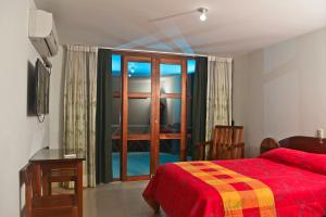 a bedroom with a red bed and a glass door at Ecolodge El Palmero in Mazamari