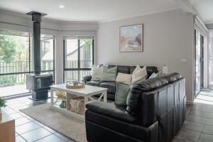 a living room with a leather couch and a table at Acacia at Boardwalk Villas in Metung