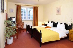 ein Schlafzimmer mit einem großen Bett und einer gelben Decke in der Unterkunft Hotel Villa Magnolia in Rödermark