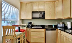 a kitchen with wooden cabinets and a table with a microwave at Beso Del Sol in Huntington Beach