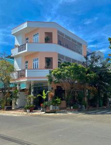 a large pink building with trees in front of it at Green Homestay Tuy Hòa in Liên Trì (4)