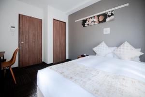a bedroom with a white bed and a wooden door at Base in Kyoto Hanazono in Kyoto