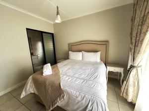 a bedroom with a bed with white sheets and pillows at The Blyde lagoon facing Pretoria in Pretoria +2 photos
