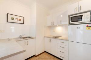 a white kitchen with a sink and a refrigerator at Hibiscus POOL VIEW Villa 49b in Port Douglas