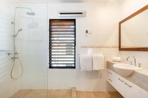 a white bathroom with a sink and a shower at Hibiscus POOL VIEW Villa 49b in Port Douglas