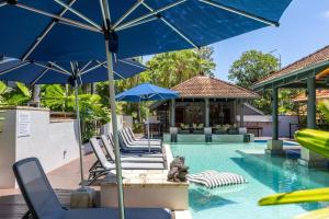 a swimming pool with chairs and umbrellas and a pool at Hibiscus POOL VIEW Villa 49b in Port Douglas