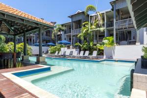 a swimming pool at a resort with chairs and umbrellas at Hibiscus POOL VIEW Villa 49b in Port Douglas