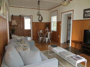 a living room with a white couch and a table at Bakery Cottage in Mangonui