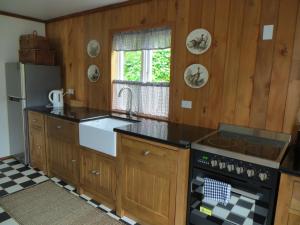 a kitchen with wooden cabinets and a sink and a stove at Bakery Cottage in Mangonui