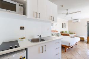 a kitchen with a sink and a bed in a room at Honeymoon Spa Suite 53 in Port Douglas