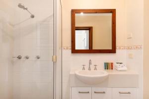 a bathroom with a sink and a shower with a mirror at Honeymoon Spa Suite 53 in Port Douglas +7 photos