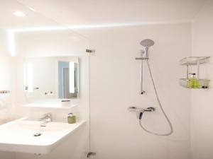 a white bathroom with a shower and a sink at Appartements nicht weit von der Donau in Linz