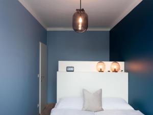 a bedroom with a white bed with a blue wall at Appartements nicht weit von der Donau in Linz