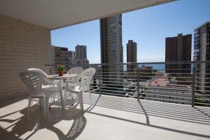 a balcony with a table and chairs and a view of the city at Apartamentos Niza in Benidorm