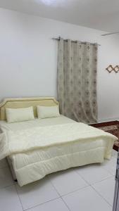 a bed in a white room with a curtain at Maqal Guesthouse in Muqal +7 photos
