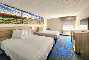 a hotel room with two beds and a painting on the wall at Days Inn & Suites by Wyndham New Iberia in New Iberia