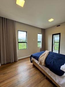 a bedroom with a bed and two windows at Mansão Luxuosa em Condominio in Belo Horizonte