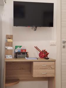 a television hanging on a wall above a wooden dresser at Casa Carruvedda in Avola
