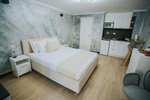 a bedroom with a large white bed and a kitchen at Storia in Piatra Neamţ