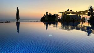 a swimming pool with an umbrella and the ocean at Haya Hotel And Spa in Tabarja