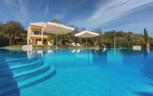 a swimming pool with blue water and umbrellas at Villa Stefania in Agios Georgios Pagon +43 photos