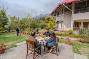a group of people sitting around a table in a yard at SaffronStays Casa Octavia in Bhīm Tāl