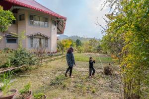 a woman and a child walking in the yard of a house at SaffronStays Casa Octavia in Bhīm Tāl +8 photos