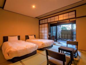 a bedroom with two beds and a balcony at Hakone Kowakien Mikawaya Ryokan in Hakone