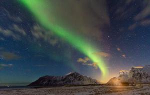 an aurora in the sky with mountains in the background at Villa Bryggekanten - by Classic Norway Hotels in Henningsvær