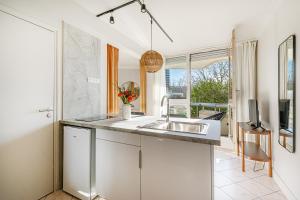a kitchen with a sink and a tv on a wall at The Lake Aurora Suite - Duke Housing in Créteil