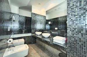 Baño de azulejos negros con 2 lavabos y aseo en Art Residence Krocinova, en Praga