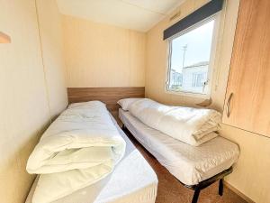 two beds in a small room with a window at 6 Berth Caravan For Hire With Decking At Manor Park In Norfolk Ref 23017S in Hunstanton +13 photos