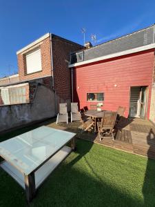 a patio with a table and chairs and a building at Idéal groupe tarif long séjour maison 4chambres 8lits 2salles de bain 3wc terrasse stationnement gratuit in Valenciennes