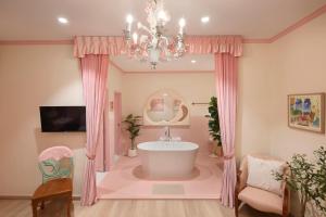 a bathroom with a tub and a chandelier at Kitsch Hotel in Bangkok